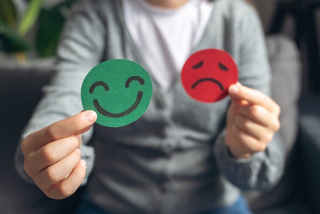 Selective focus of female hands holding happy and angry face paper sit on sofa. | TMZ Behavioral Care in Davie, FL