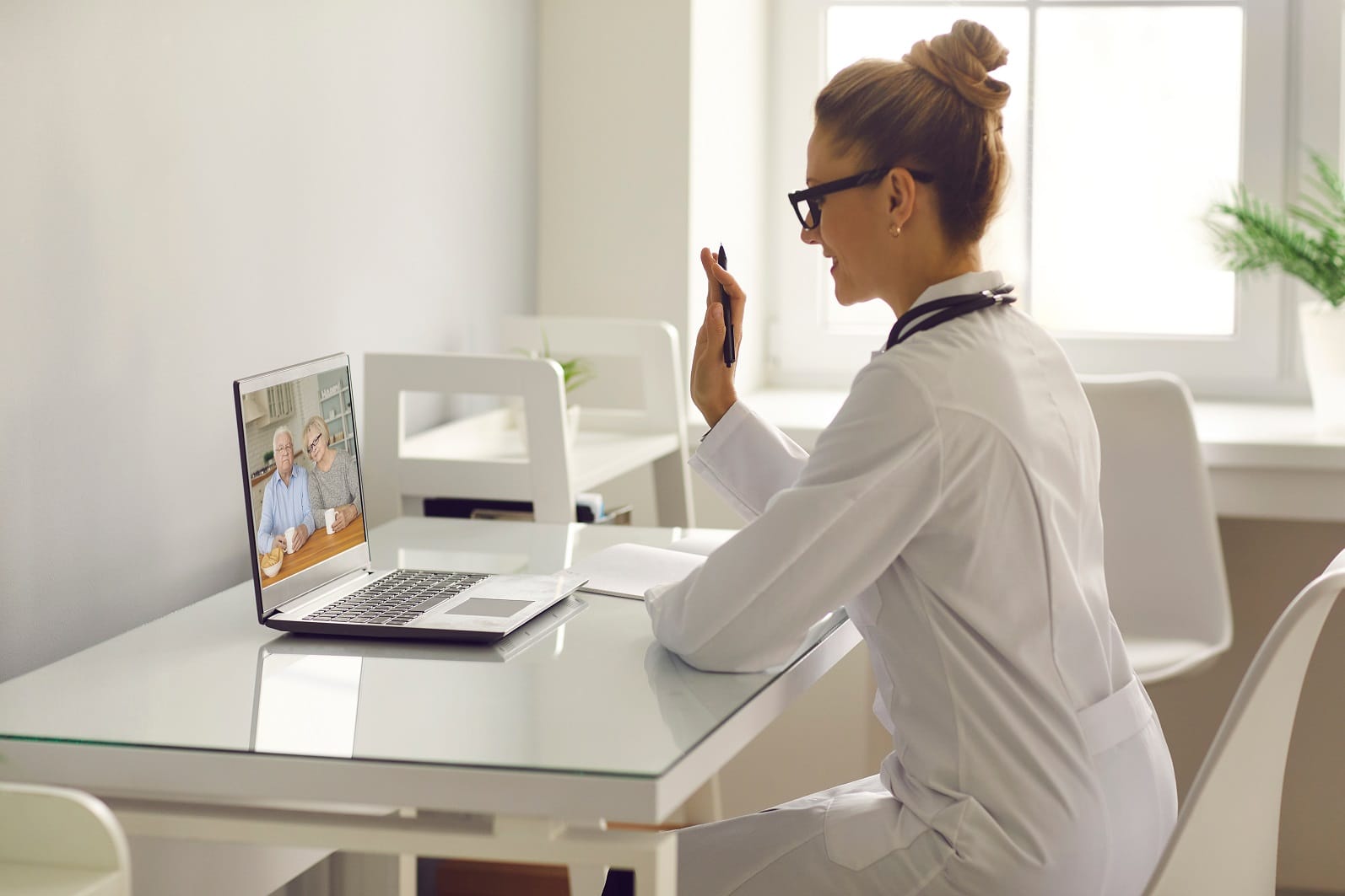 Family practitioner video calling senior couple and waving hand at laptop computer | TMZ Behavioral Care in Davie, FL