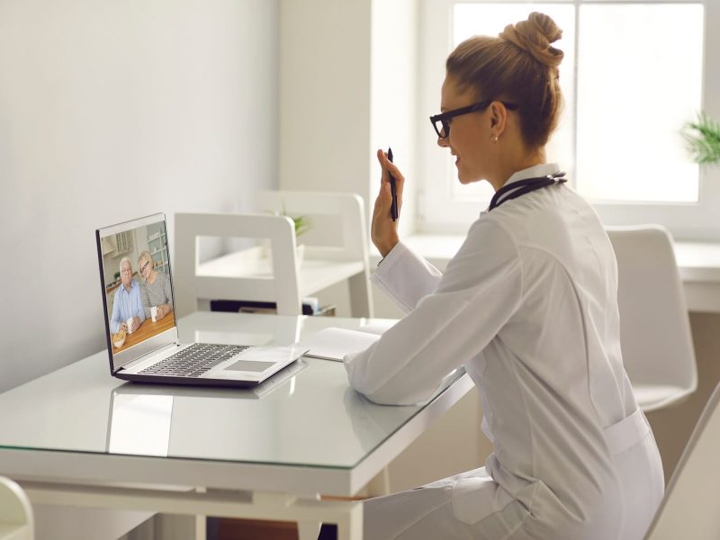 Family practitioner video calling senior couple and waving hand at laptop computer | TMZ Behavioral Care in Davie, FL